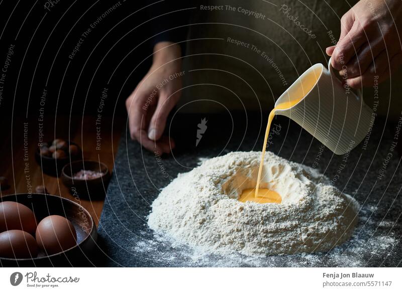 Frisch zubereiteter Teig mit Eiern, handgemachtes Küchenvergnügen in stimmungsvollem Low-Key-Licht Schuss Gießen Aktion Teig herstellen Prozess backen
