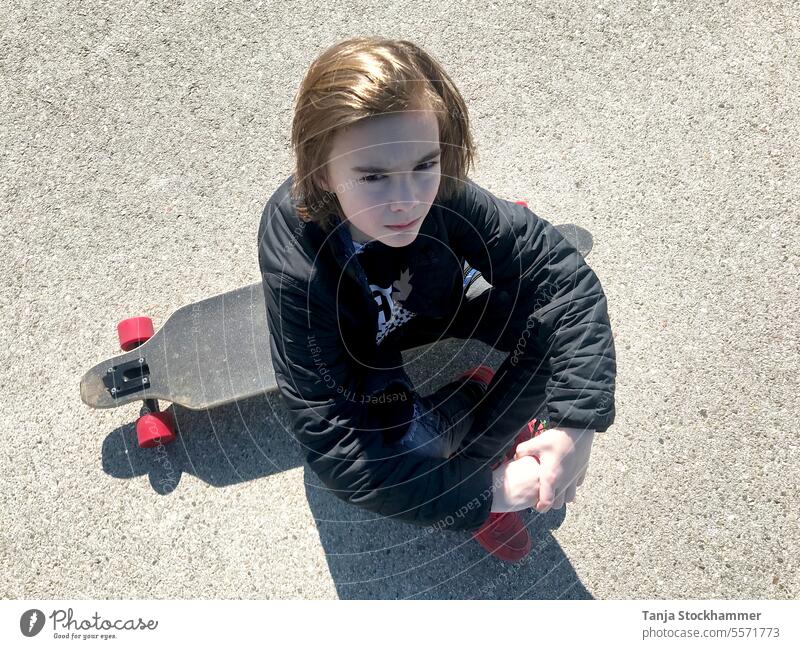 Junge mit Skateboard sitzend knabe Sport hobby ernster Blick sportlich Freizeit & Hobby Freizeitaktivität freizeitbeschäftigung Freizeitsport