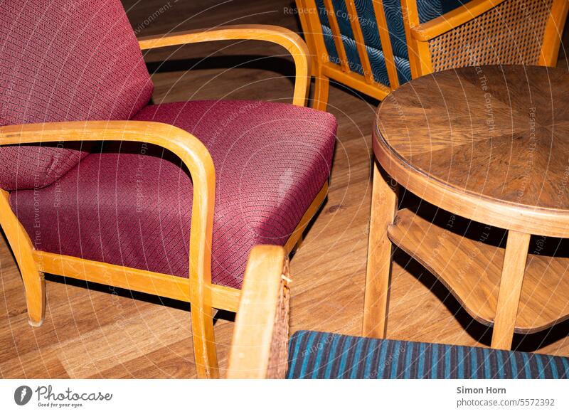 Sessel stehen ungeordnet um einen runden Tisch durcheinander Detailaufnahme runder Tisch Treffpunkt Holzboden Konglomerat Sitzgelegenheit sitzen Stuhl Tonalität