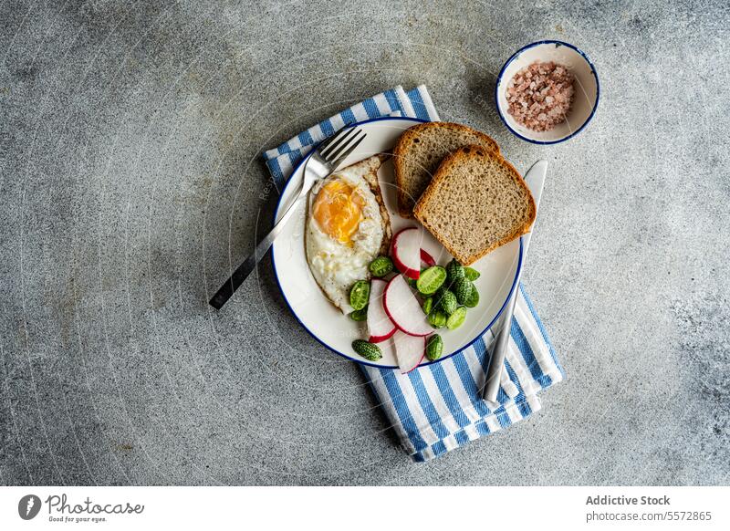 Gesunder Mittagsteller auf gestreiftem Tuch Frühstück Ei Brot Rettich Gemüse grün Stoff blau weiß Schalen & Schüsseln rosa Salz grau Textur Hintergrund Teller