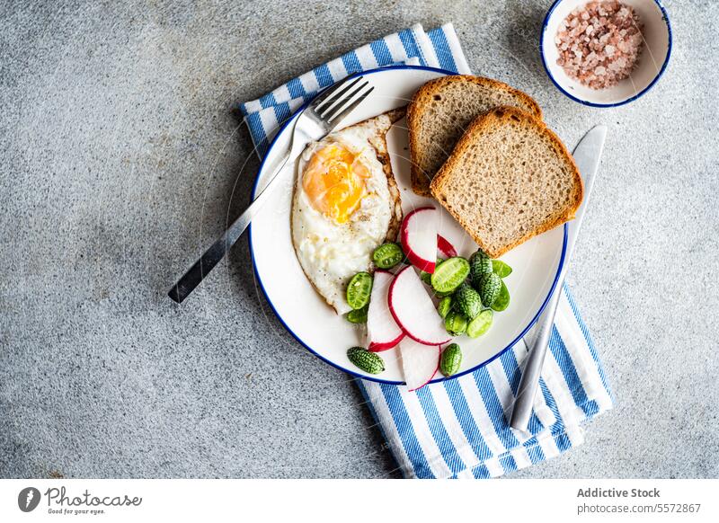 Gesunder Mittagsteller auf gestreiftem Tuch Frühstück Ei Brot Rettich Gemüse grün Stoff blau weiß Schalen & Schüsseln rosa Salz grau Textur Hintergrund Teller