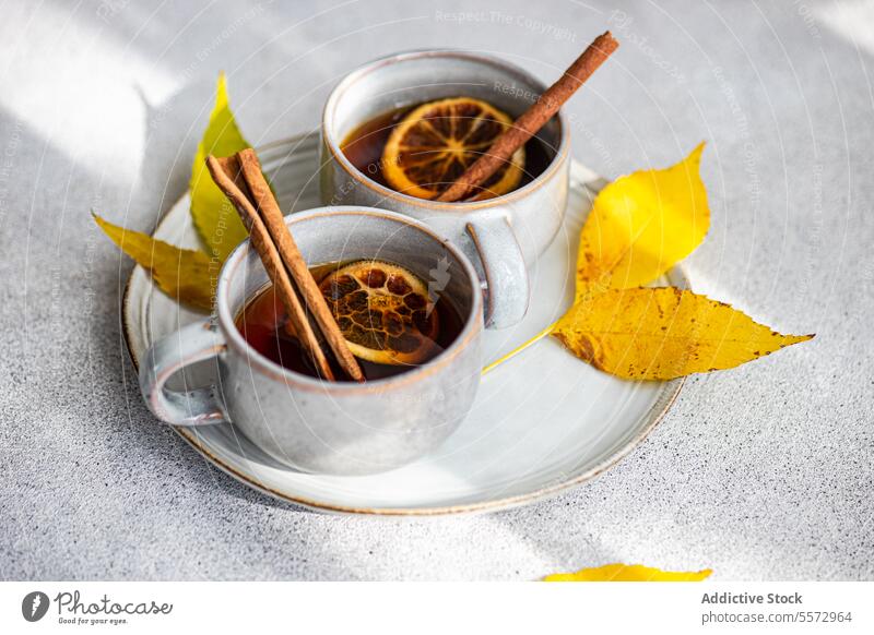 Gewürztee mit Herbstblättern Tee gewürzt Tasse Zimt Anis getrocknet orange Scheibe Blatt gelb Getränk warm Garnierung grau Oberfläche Keramik trinken aromatisch