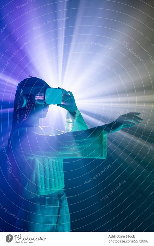 Frau mit VR-Brille gestikuliert über Neonlichter Schutzbrille virtuell Realität Licht gestikulieren orange Zopf Headset Technik & Technologie eintauchen