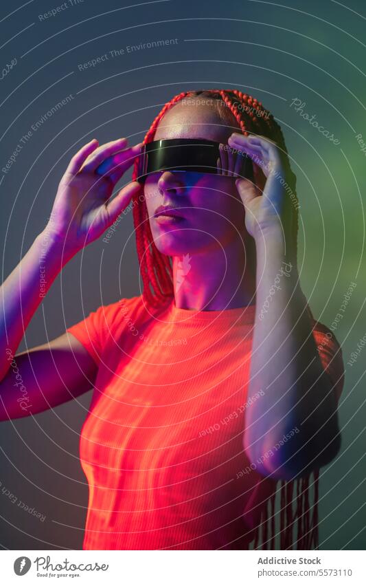 Frau mit futuristischer VR-Brille im Studio Schutzbrille Erfahrung virtuell Realität Frisur Studioaufnahme Licht erweitert Cyberspace Innovation Simulator