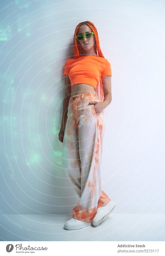 Frau mit orangefarbenen Zöpfen auf weißem Hintergrund schön jung selbstbewusst stylisch Zopf Mode posierend Sonnenbrille Model Einstellung Studioaufnahme