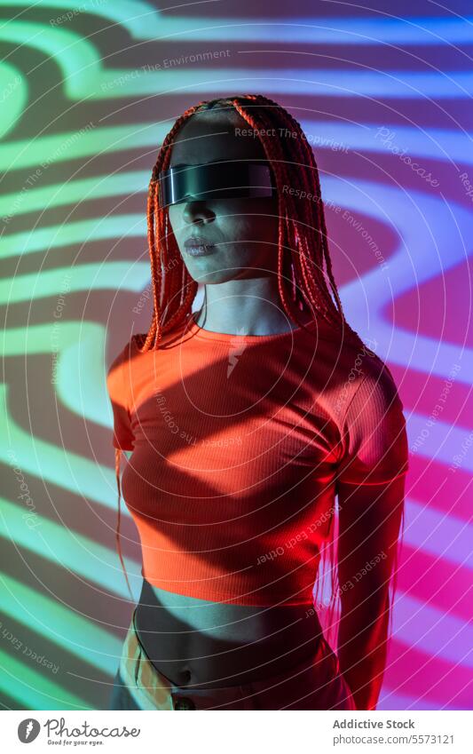 Frau erkundet den Cyberspace mit VR-Brille Headset Windstille orange Zopf Erfahrung erweitert virtuell futuristisch Metaversum jung cool Studioaufnahme