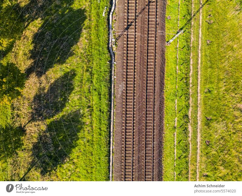 Eine Eisenbahnlinie auf dem Lande in der Sonne direkt von oben Bahnlinie Spuren zwei Gleise führt Natur Personennahverkehr Regionalverkehr Landschaft