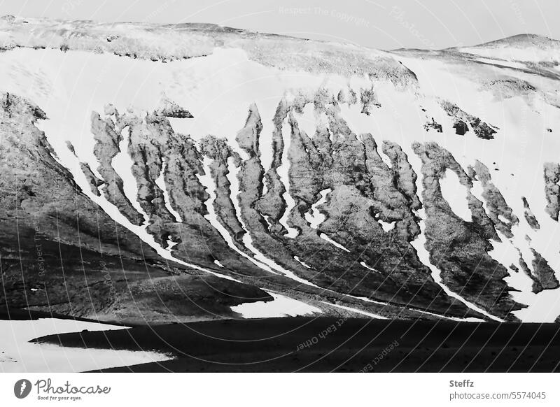 Blick auf eine Bergseite mit Schneeschmelze auf Island Nordisland Hügelseite felsig Schneereste Schneeformen Islandwetter Formen geheimnisvoll einsam