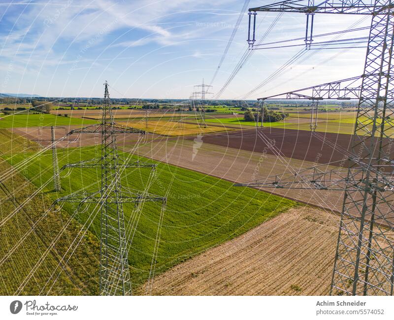 Luftaufnahme zwischen Strommasten mit Stromleitungen am Horizont Drohnen-Perspektive Bereiche mehrere Hochspannungsmasten ländlich viele