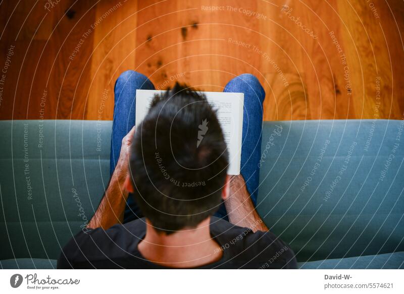 lesen bildet - Mann auf dem Sofa vertieft in ein Buch Wissen Bildung Literatur konzentriert fantasie spaß Freude lernen Konzentration Gedanken anonym sitzen