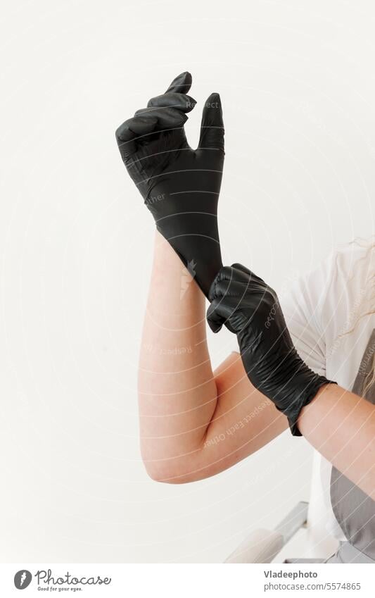 Frau zieht schwarze Gummihandschuhe an. Weißer Hintergrund Handschuh Klinik professionell Medizin Finger Arbeit nageln Maniküre medizinisch Pflege weiß