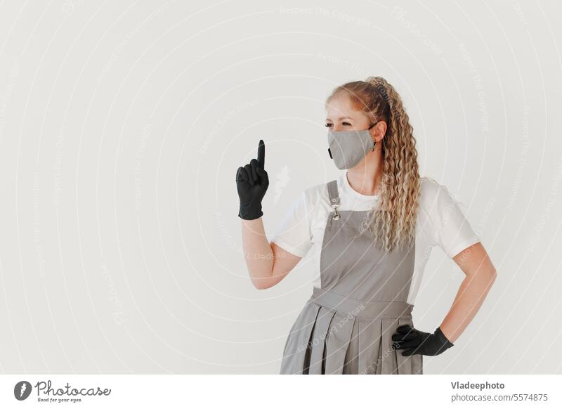 Frau Schönheit Industrie Meister in grauer Uniform und schwarze Handschuhe zeigt Aufmerksamkeit Zeichen auf weiß Finger jung Person Medizin medizinisch Pflege