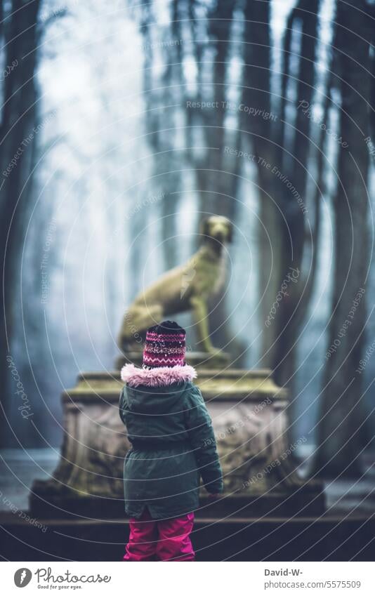 Kind erkundet die mystische Umgebung Erkunden Neugier Mystisch Statue Winter Spaziergang Unheimlich Wald Düster Angst Furcht unheimlich dunkel geheimnisvoll