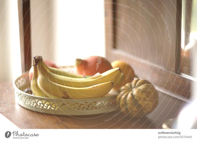 Herbstliches Arrangemenemt aus Obst und Gemüse auf der heimischen Anrichte weich warm Licht Sonnenlicht Tageslicht Bananen Stillleben Kürbis Erntedank Orange