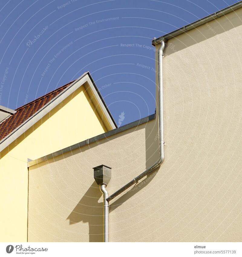 gelber Hausgiebel und fensterlose Rückseite eines Hauses mit Dachrinne und Fallrohr Dachgiebel Hauswand wohnen Wohnhaus Strukturen & Formen Dreieck Blog