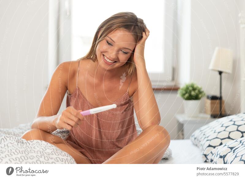 Junge glückliche Frau wegen des Ergebnisses des Schwangerschaftstests Prüfung Ovulation schwanger positiv Teenager jung Erwachsener Vorfreude lässig Kaukasier