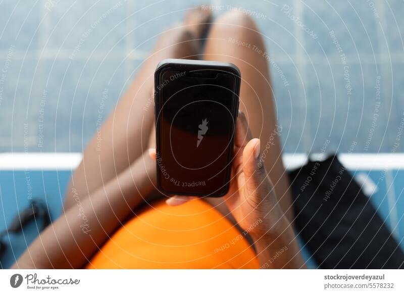 Zenithale Nahaufnahme eines Smartphones, das von einer schwarzen Frau im Schwimmbad benutzt wird Beteiligung Technik & Technologie Lifestyle jung erhitzt