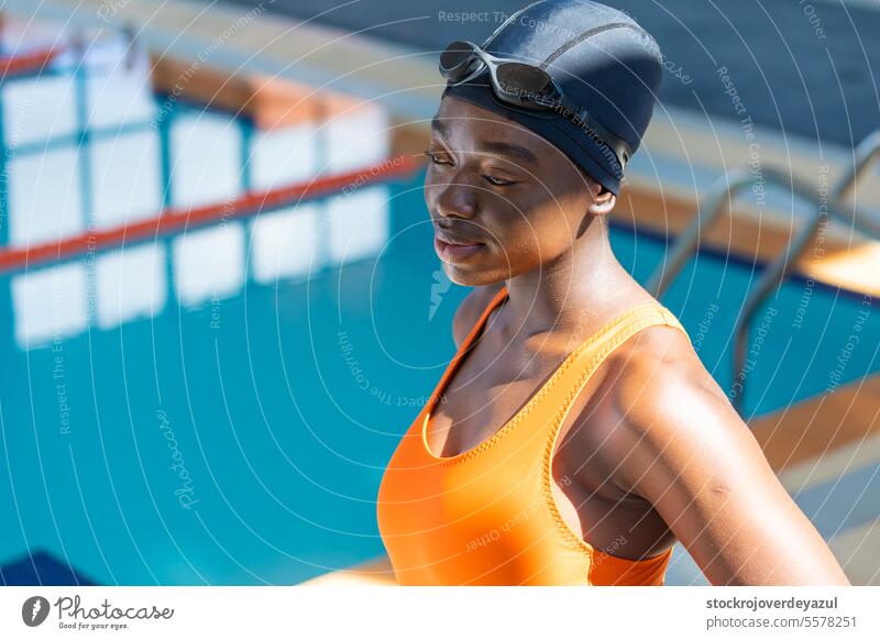 Porträt einer schwarzen jungen Frau, die am Schwimmbad steht Frauen Pool schwimmen Fitness Gesundheit Wasser Schutzbrille nass erhitzt orange blau