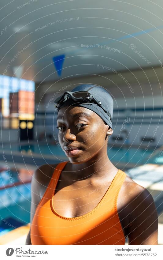 Nahaufnahme eines Porträts einer schwarzen jungen Frau, die am Swimmingpool in die Kamera schaut Schwimmer Pool Sport Schwimmbad erhitzt Badeanzug orange