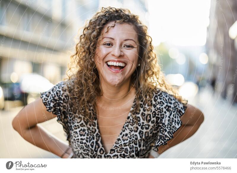 Porträt einer lächelnden jungen Frau mit lockigem Haar in der Stadt junger Erwachsener Straße außerhalb Selbstvertrauen Lächeln genießen Lachen Freude Spaß
