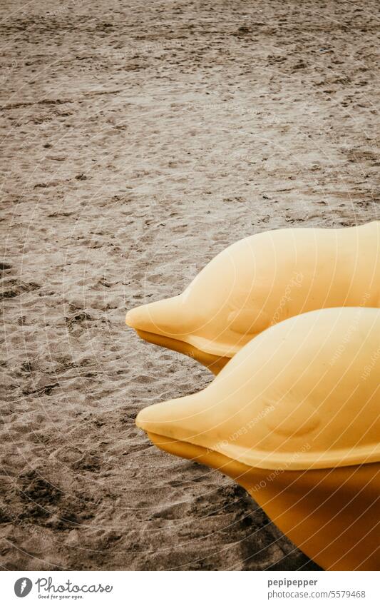 Zwei Delphin-Gesichter eines Tretbootes am Strand liegend Delphine Schwimmen & Baden Meer Außenaufnahme Stranddüne Sand Sandstrand Delfin gelb Wasser