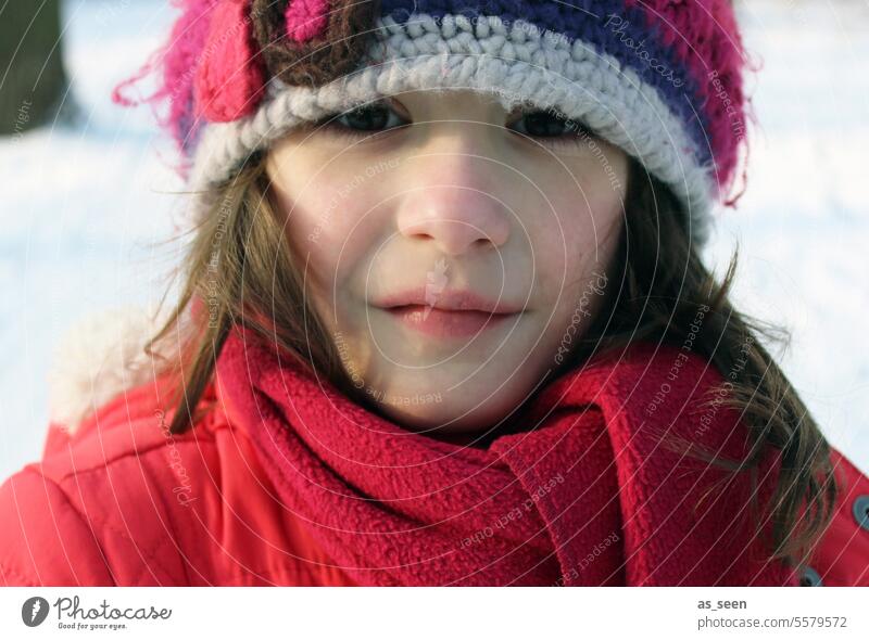 Mädchen mit Mütze im Winter Blick in die Kamera brünett verfroren kalt Schnee Häkelmütze Jacke rot braune Augen Schal Kind Kindheit Mensch Außenaufnahme