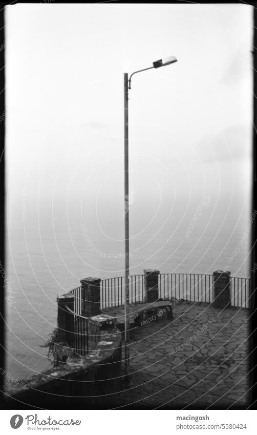 Aussichtspunkt aufs Meer mit Laterne alt Einsamkeit Schwarzweißfoto Traurigkeit Vergänglichkeit analog analoge fotografie schwarzweiß Schwarzweißfotografie