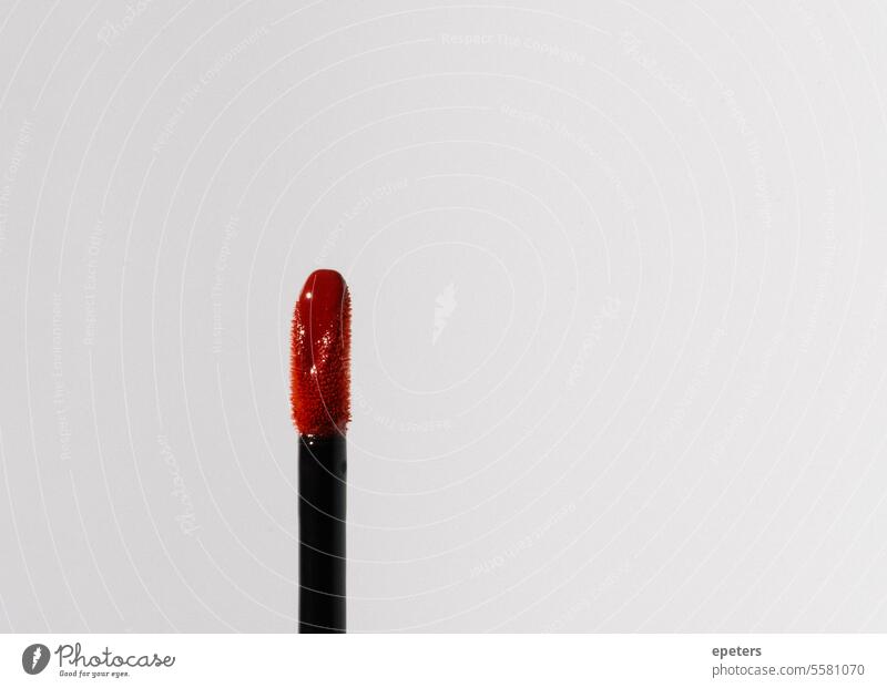 Nahaufnahme eines Lipgloss-Applikators mit rotem Glanz auf neutralem Hintergrund Kosmetik Creme Makro Schönheitsprodukt Make-up Schönheitsindustrie