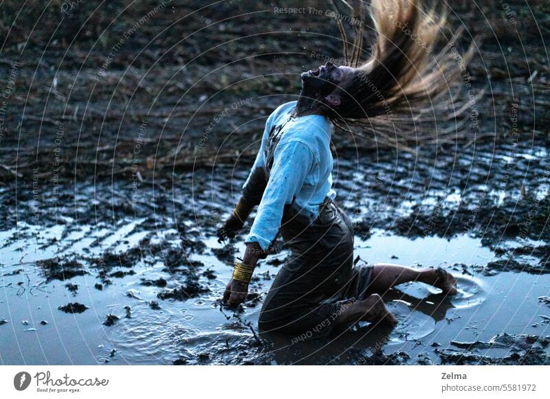 Dramatisches Porträt einer jungen Frau, die im schwarzen Schlamm auf einem Feld kniet, Schrei der Verzweiflung verzweifelt weinen schreien kniend dramatisch