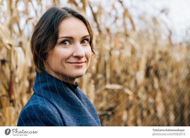 Porträt einer attraktiven jungen Frau im Herbstmantel im Kornfeld Mantel Reihen Mais Feld fallen im Freien ländlich Landschaft Ernte saisonbedingt