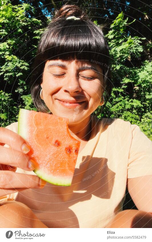 Porträt einer lächelnden Frau mit geschlossenen Augen, die ein Stück Wassermelone hält geschlossene Augen Sommer Sonne Gesicht genießen gesund Obst Selfie