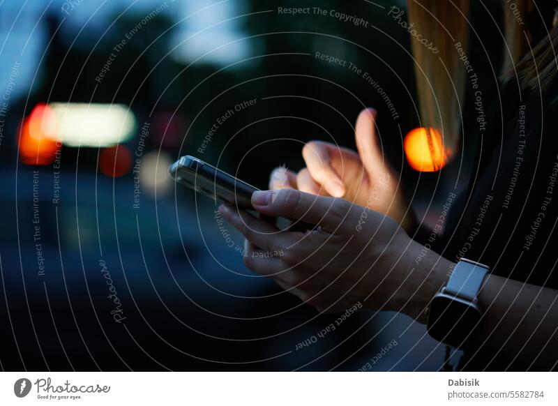 Frau benutzt Smartphone auf abendlicher Straße Nacht Großstadt Mitteilung online benutzend im Freien Browsen Hand Beteiligung Gerät Business soziale Netzwerke