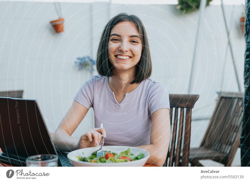 Junge Freiberuflerin arbeitet am Laptop und isst Salat, gesunde Menschen, arbeiten zu Hause Konzept. Tablette Ergänzung Frau Glück Schmerztablette Vitamin