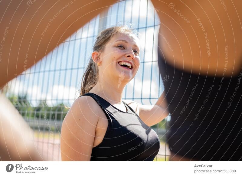 Mädchen lehnt an einem Zaun auf einer Leichtathletikbahn und spricht mit anderen Mädchen. Sport Frau Frauen Fitness Gesundheit passen Übung Erwachsener