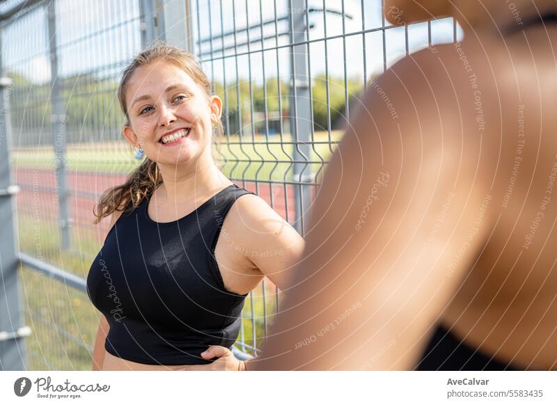 Universitätsstudentin, die sich neben einem Zaun auf der Leichtathletikbahn ihrer Hochschule ausruht und Zeit mit Freunden verbringt Frauen Fitness passen Sport