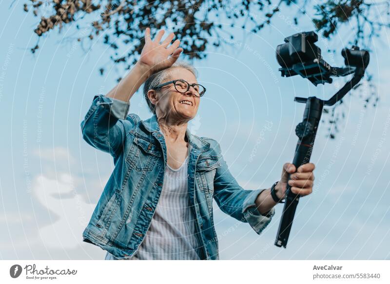 Ältere fröhliche Frau, die ein Video für ihre Familie aufnimmt, in dem sie ihren Urlaub erklärt. Alter Fotograf. Ruhestand Erwachsener Person Luftschlange live