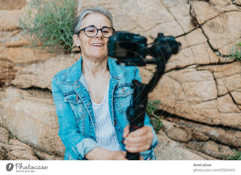 Ältere fröhliche Frau, die ein Video für ihre Familie aufnimmt, in dem sie ihren Urlaub erklärt. Alter Fotograf. Senior Ruhestand Luftschlange live Lifestyle
