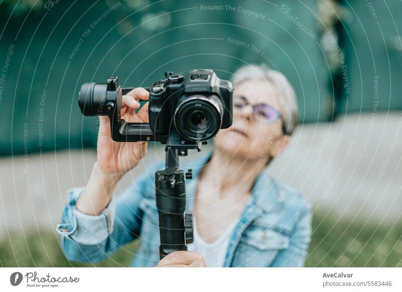 Konzentrierte Seniorin, die mit ihrer Kamera Fotos und Videos aufnimmt und sich darauf vorbereitet. Ruhestand Luftschlange live Person Frau Fotokamera jung