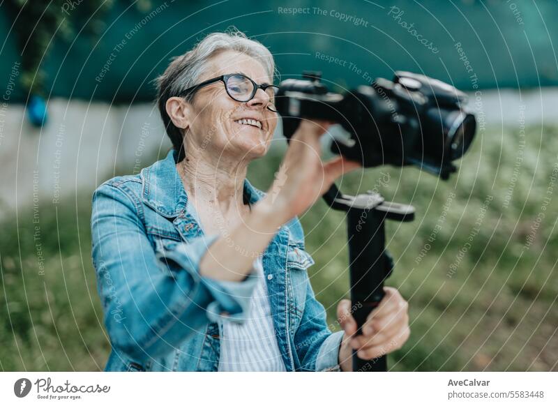 Konzentrierte Seniorin, die mit ihrer Kamera Fotos und Videos aufnimmt und sich darauf vorbereitet. Frau Ruhestand Frauen Erwachsener Person Lifestyle