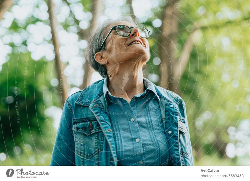 Porträt einer älteren Dame, die die Natur im Wald genießt und bei einem Spaziergang frische Luft außerhalb der Stadt atmet mental Gesundheit Frau Ruhestand