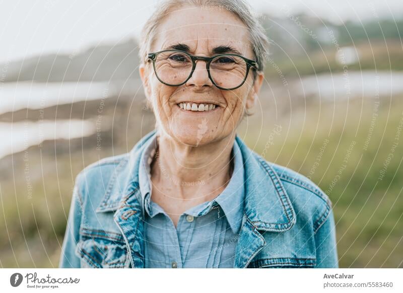 Lächelnde erwachsene Frau mit kurzen grauen Haaren, die einen Strand besucht und sich bei einem Spaziergang mit der Natur verbindet. mental Gesundheit Ruhestand