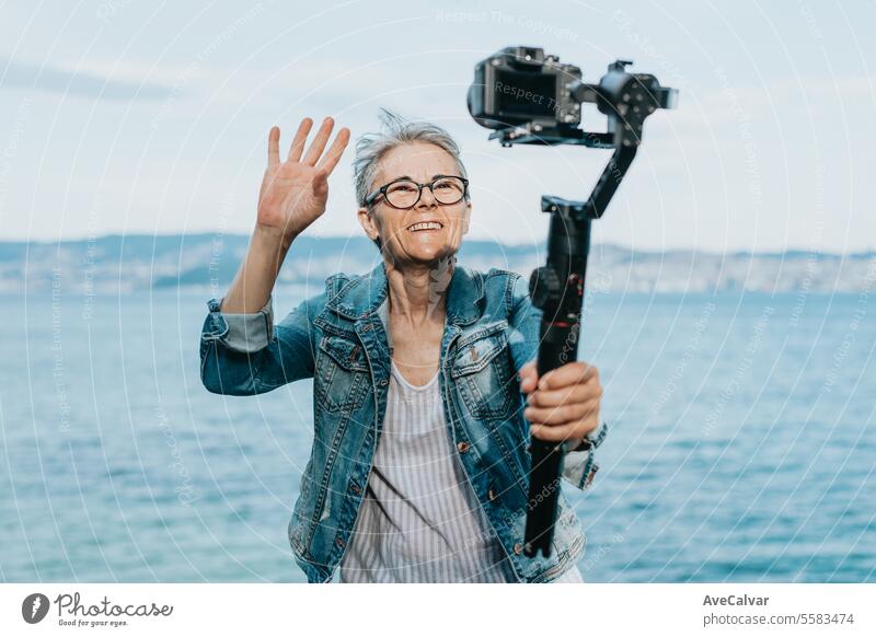 Ältere fröhliche Frau, die ein Video für ihre Familie aufnimmt, in dem sie ihren Urlaub erklärt. Alter Fotograf. Senior Ruhestand Luftschlange live Lifestyle