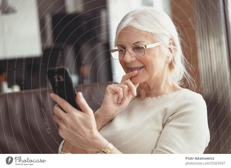 Schöne ältere Frau textet zu Hause Senior Smartphone Lächeln Rentnerin 60s Jahre alt gealtert schön lässig Glück sozial Medien Technik & Technologie Anruf