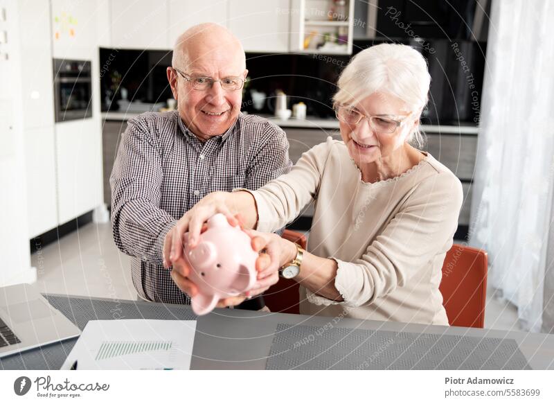 Älteres Paar versucht, die Ersparnisse zu erhalten Senior Geld Einsparungen Sparschwein gealtert lustig Bank Kaukasier Geldmünzen schütteln Rechnung Familie