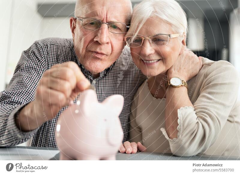 Älteres Ehepaar steckt die Münze in das Sparschwein Einsparungen Paar Senior Haushaltsplan reif heimwärts in den Ruhestand getreten Blick Innenbereich Kontor