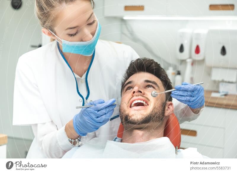 Mann lässt Zähne beim Zahnarzt untersuchen Zahnmedizin Erwachsener Bleiche Aufhellung weiß Lächeln Pflege Kaukasier Ästhetik Stuhl prüfen Check-up Sauberkeit