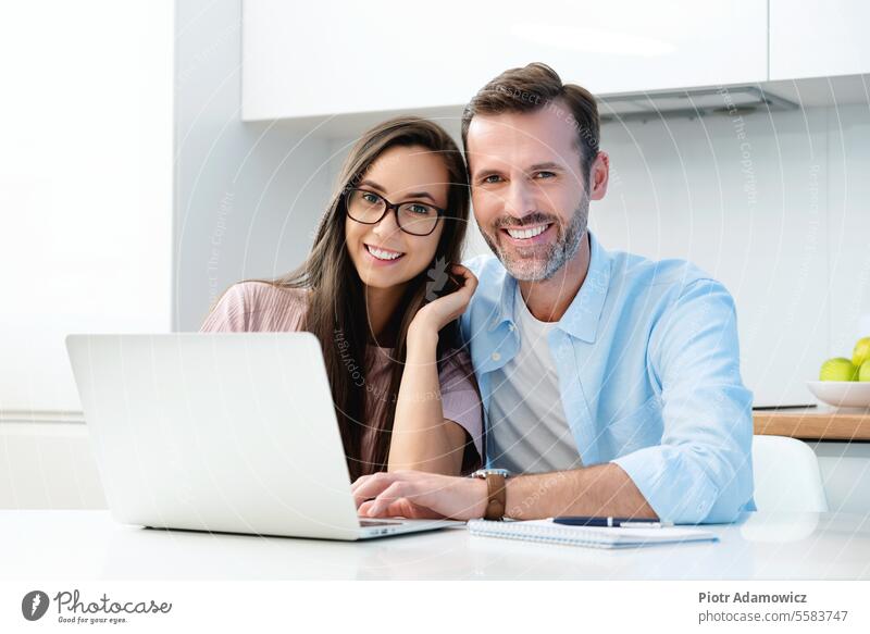 Lächelndes Paar, das am Computer sitzt Glück weiß Zähne Weißeln perfekt heimwärts Laptop Haushaltsplan Familie finanziell Ausgaben Buchhaltung Erwachsener