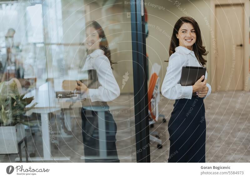 Junge Frau mit Digital-Tablet zu Fuß in der modernen Büroflur Erwachsener attraktiv schön Business Geschäftsfrau lässig heiter Mitteilung Unternehmen