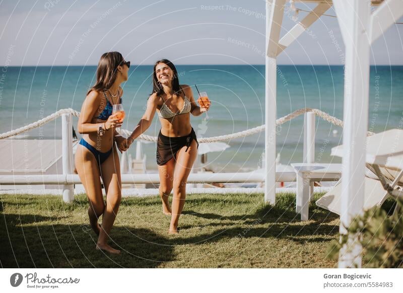 Lächelnde junge Frauen im Bikini genießen den Urlaub am Strand Erwachsener Bekleidung Tag trinken Emotion Mode Fröhlichkeit Feiertag Italien Freizeitaktivitäten
