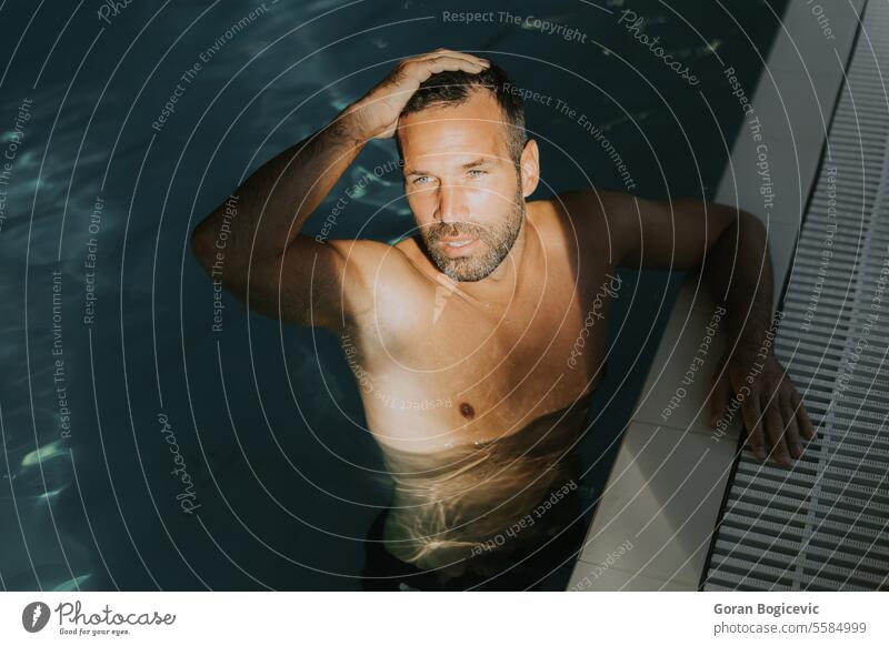 Gutaussehender junger Mann entspannt sich am Rande eines Hallenbades Kaukasier Saum Fitness attraktiv Pool Wasser Erwachsener sportlich männlich gutaussehend